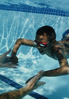 Boy (4-6) learning to swim underwater, hands reaching out